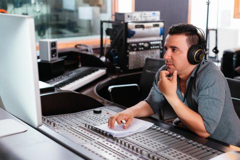 Producer sitting at computer looking at computer to hire a voice actor