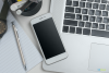 overhead picture of a phone and a computer keyboard on a desktop with a silver pen